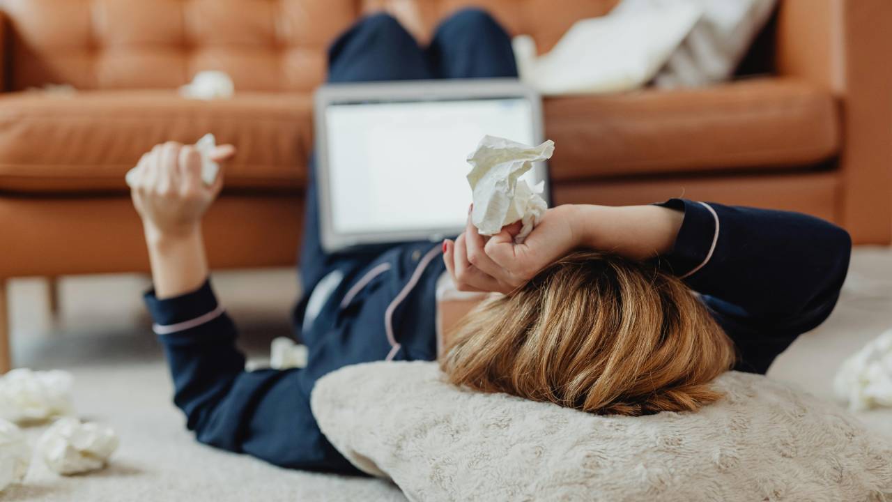 žena s vreckovkami ležiaca v obývačke na zemi